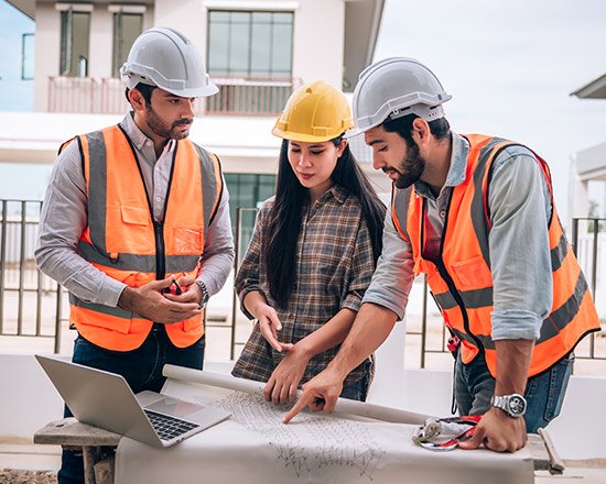Equipo de arquitectos y constructores revisando planos y maqueta de proyecto en mesa de trabajo